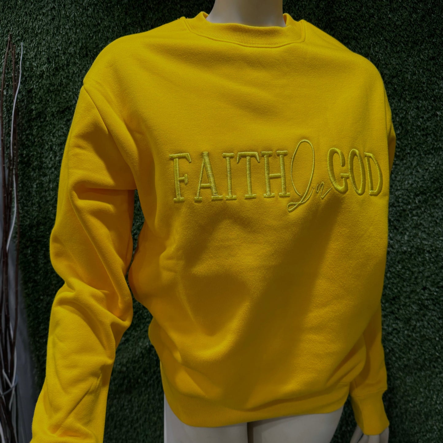 A yellow sweatshirt with 'FAITH IN GOD' embroidered on the chest.