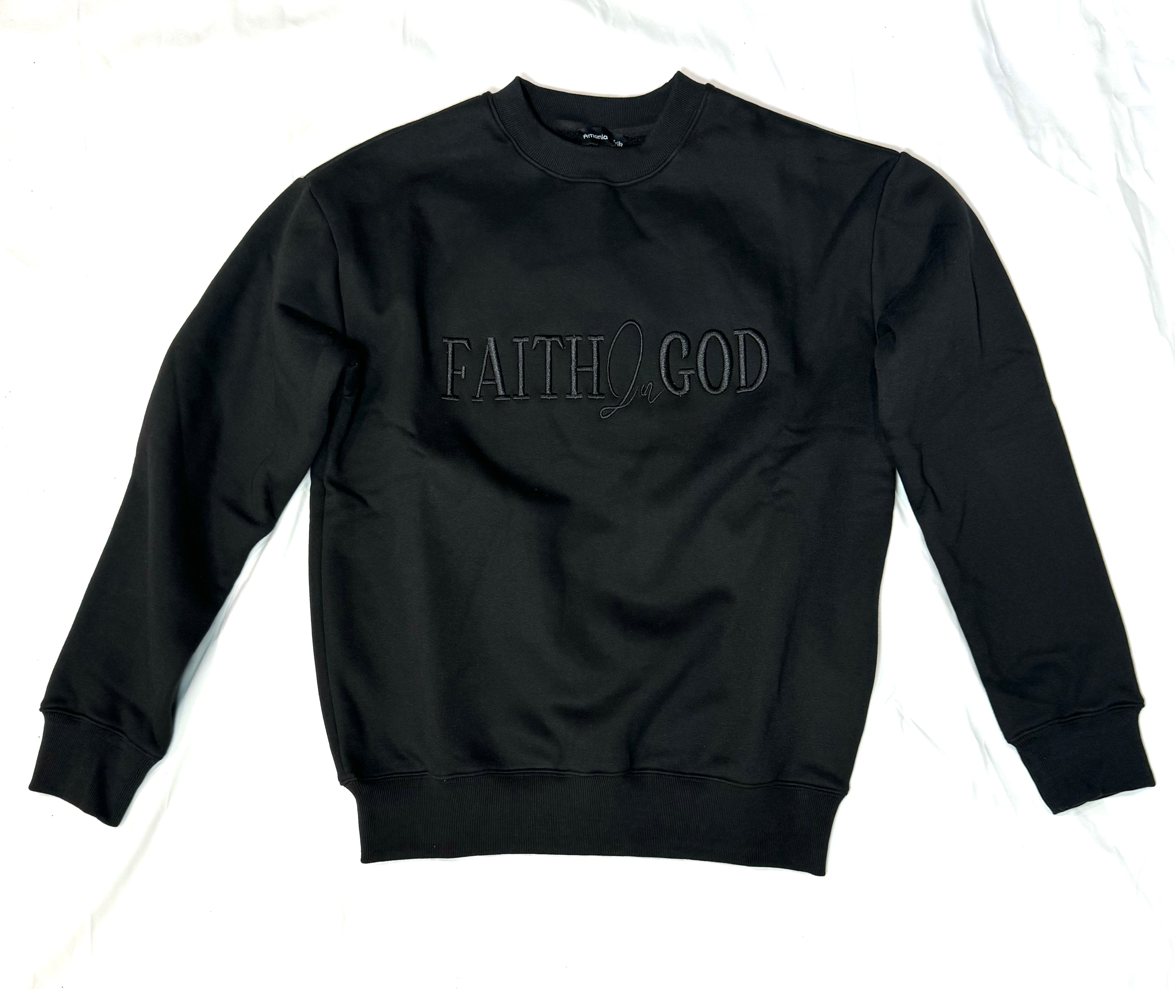 A person wearing a black sweatshirt with 'FAITH IN GOD' embroidered on the chest.